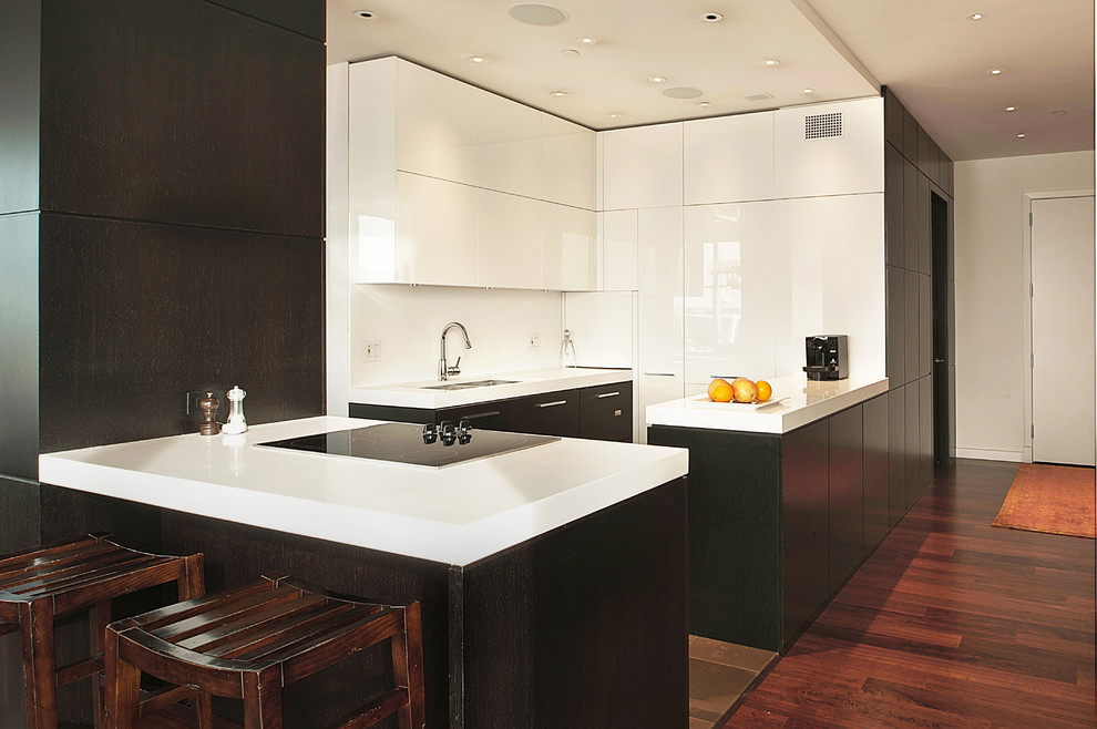 Inspiration for a mid-sized modern medium tone wood floor and brown floor kitchen remodel in New York with a double-bowl sink, flat-panel cabinets, white cabinets, quartz countertops, white backsplash, stainless steel appliances and an island