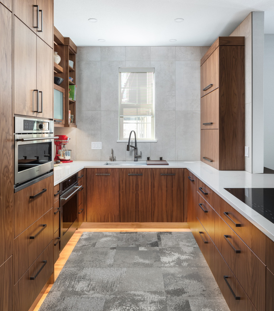 Foto di una cucina minimal di medie dimensioni con lavello sottopiano, ante lisce, ante in legno scuro, top in quarzo composito, paraspruzzi grigio, paraspruzzi con piastrelle in ceramica, elettrodomestici in acciaio inossidabile, pavimento in legno massello medio, penisola e top bianco