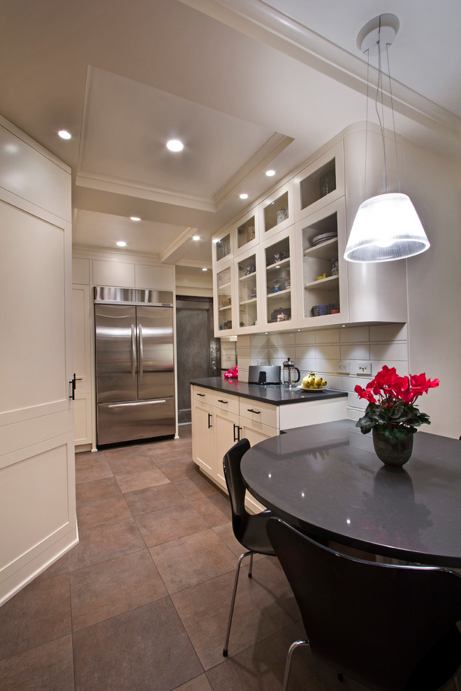Cette image montre une petite cuisine design avec un évier posé, des portes de placard blanches, un plan de travail en granite, une crédence blanche et un électroménager en acier inoxydable.