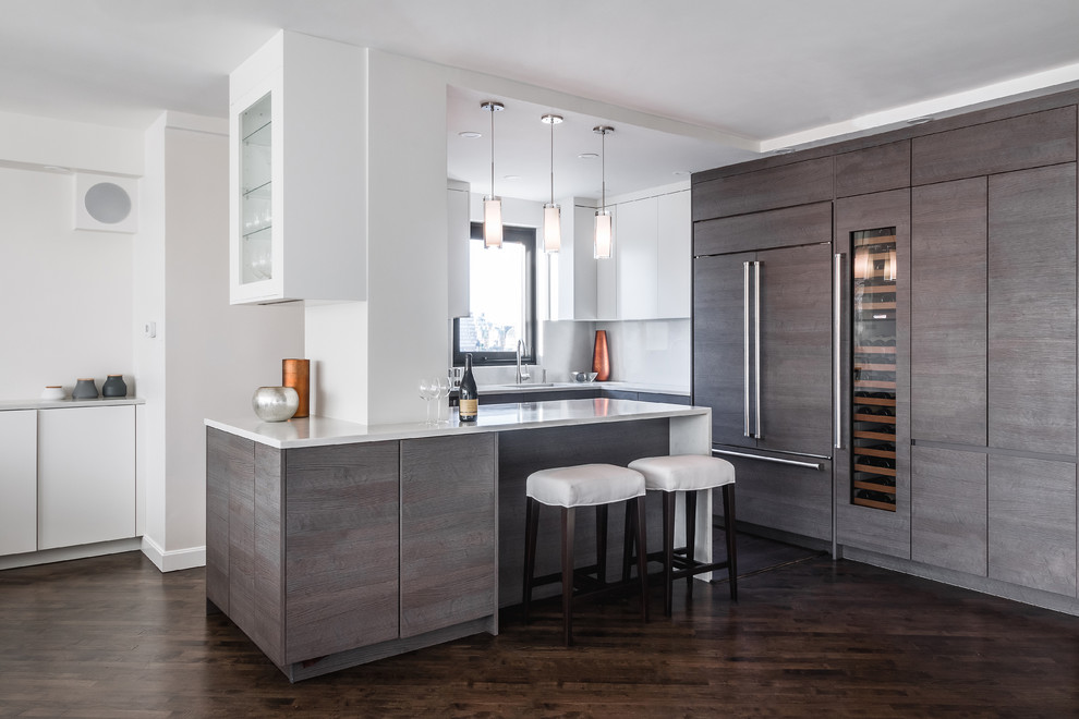 This is an example of a medium sized contemporary l-shaped kitchen in New York with flat-panel cabinets, dark wood cabinets, white splashback, integrated appliances, dark hardwood flooring, an island, brown floors, white worktops, a submerged sink, quartz worktops and stone slab splashback.