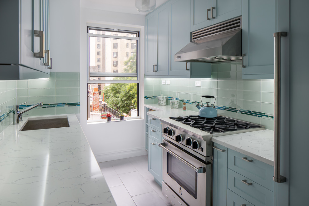 Example of a mid-sized classic galley cement tile floor and gray floor kitchen pantry design in New York with an undermount sink, shaker cabinets, blue cabinets, quartz countertops, metallic backsplash, glass tile backsplash, paneled appliances, two islands and gray countertops