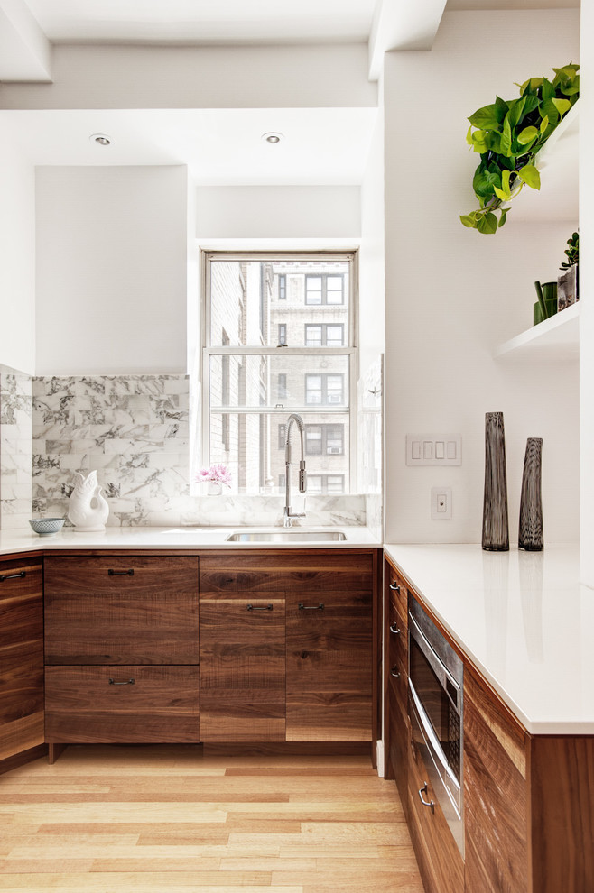Modern inredning av ett kök, med en undermonterad diskho, släta luckor, skåp i mörkt trä, flerfärgad stänkskydd, rostfria vitvaror, ljust trägolv och stänkskydd i stenkakel
