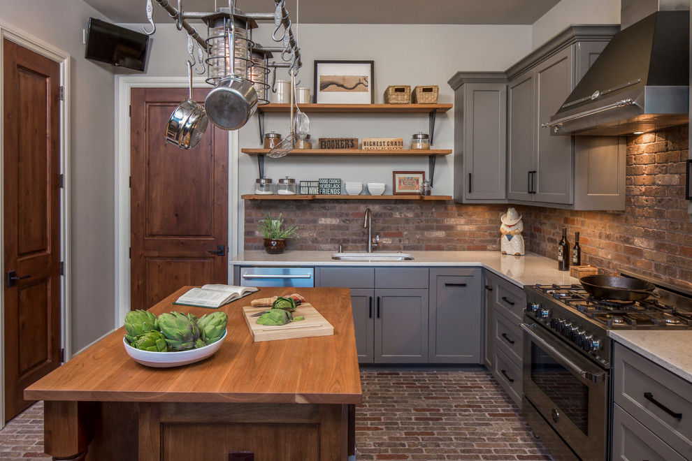 Large transitional l-shaped brick floor and brown floor enclosed kitchen photo in Austin with an undermount sink, gray cabinets, solid surface countertops, stainless steel appliances, an island, shaker cabinets, brick backsplash and brown backsplash