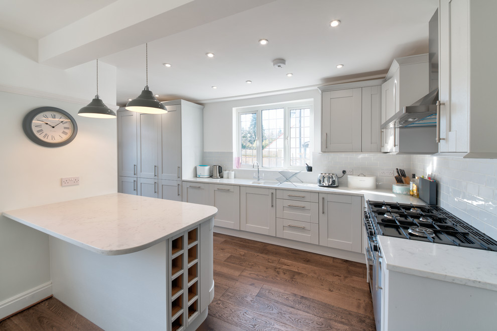 This is an example of a medium sized l-shaped kitchen/diner in London with a submerged sink, shaker cabinets, grey cabinets, granite worktops, grey splashback, brick splashback, stainless steel appliances, dark hardwood flooring, an island, brown floors and multicoloured worktops.