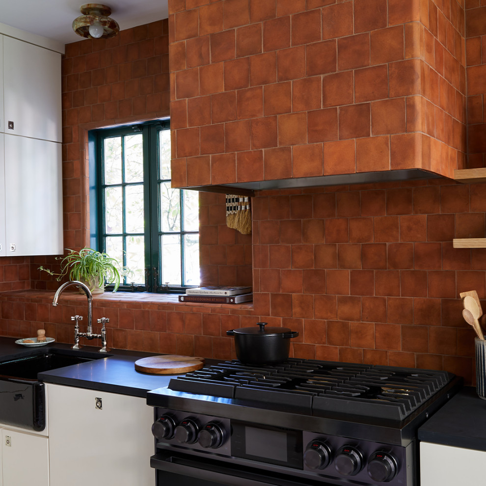 Пример оригинального дизайна: кухня с коричневым фартуком, фартуком из терракотовой плитки и черной столешницей