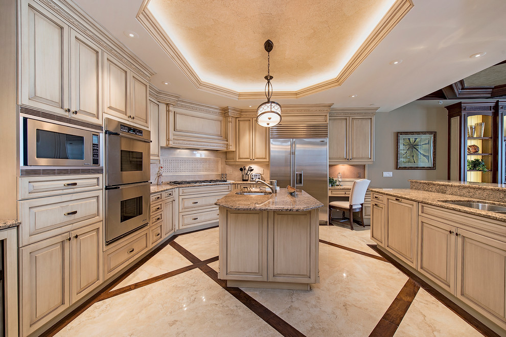 Photo of a traditional u-shaped kitchen in Denver with a submerged sink, raised-panel cabinets, beige cabinets, beige splashback, stainless steel appliances, an island and beige floors.