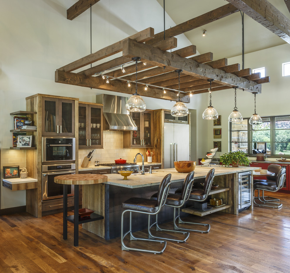Example of a mountain style galley medium tone wood floor and brown floor eat-in kitchen design in Other with flat-panel cabinets, medium tone wood cabinets, white backsplash, subway tile backsplash, stainless steel appliances, an island and gray countertops