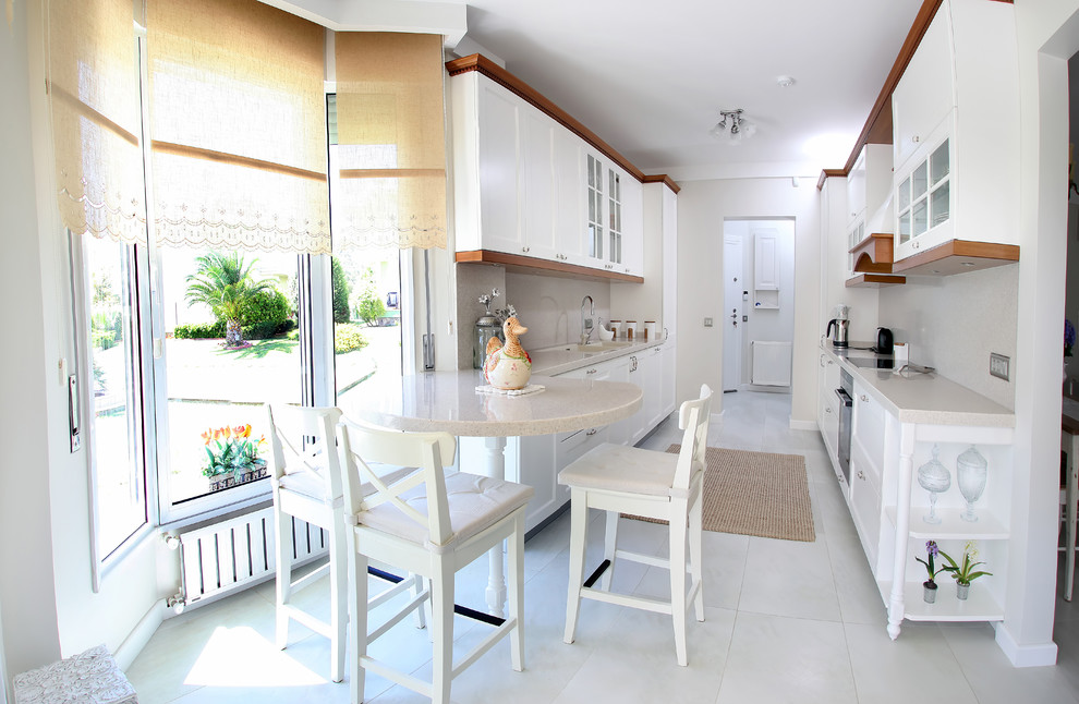 Modelo de cocina clásica con armarios con paneles empotrados, puertas de armario blancas, salpicadero beige y electrodomésticos de acero inoxidable