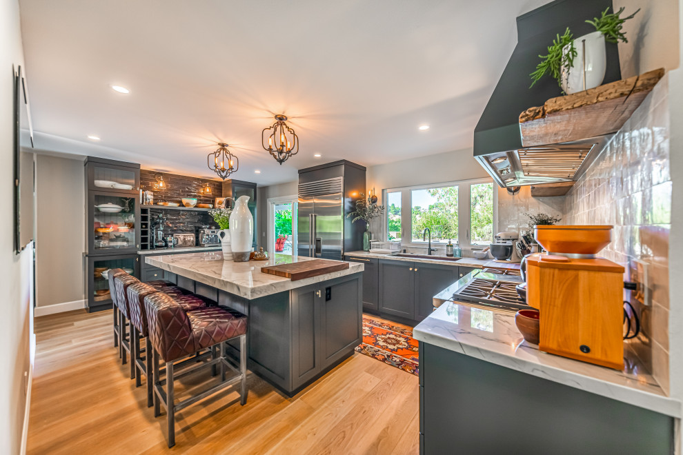 Exempel på ett stort modernt grå grått kök, med en undermonterad diskho, skåp i shakerstil, grå skåp, bänkskiva i kvartsit, svart stänkskydd, stänkskydd i porslinskakel, rostfria vitvaror, ljust trägolv, en köksö och brunt golv