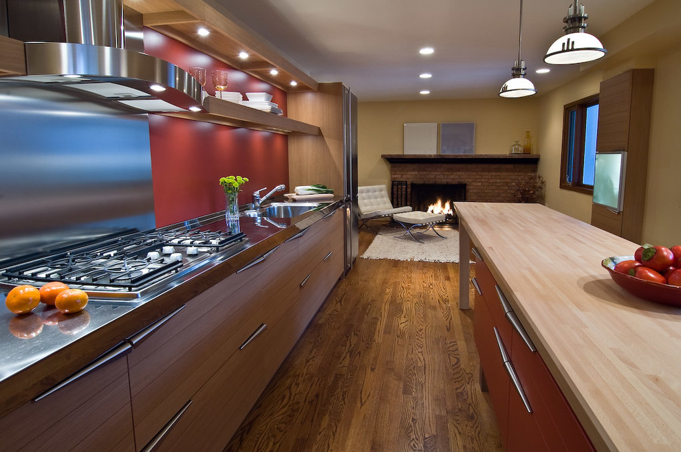ワシントンD.C.にある広いモダンスタイルのおしゃれなキッチン (アンダーカウンターシンク、フラットパネル扉のキャビネット、淡色木目調キャビネット、木材カウンター、パネルと同色の調理設備、無垢フローリング、茶色い床) の写真