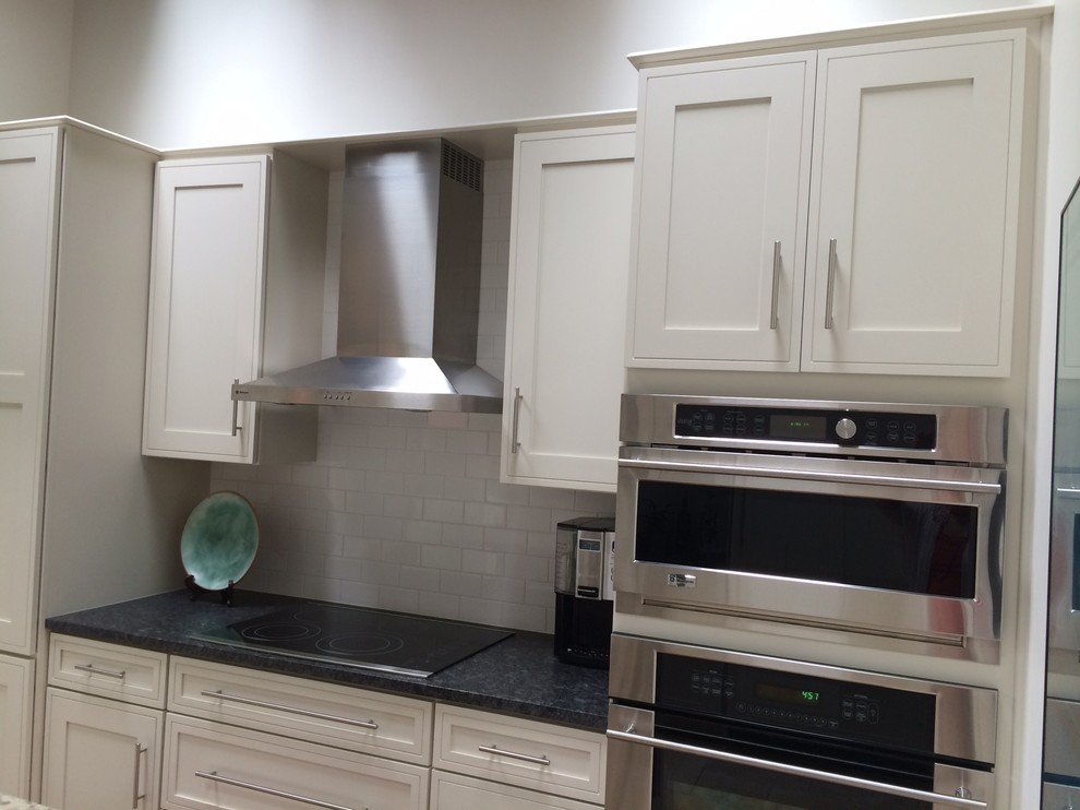 Design ideas for a small traditional galley kitchen/diner in Wilmington with a belfast sink, shaker cabinets, white cabinets, granite worktops, white splashback, metro tiled splashback, porcelain flooring, an island and stainless steel appliances.