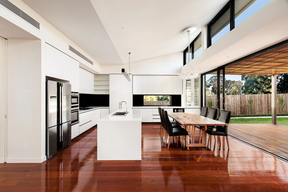 Design ideas for a contemporary kitchen in Melbourne with flat-panel cabinets, white cabinets, black splashback, stainless steel appliances, medium hardwood flooring and an island.
