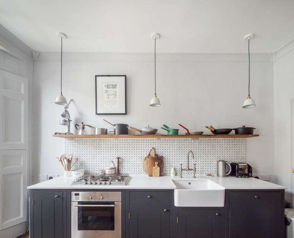Immagine di una piccola cucina classica con lavello stile country, ante lisce, ante nere, top in quarzite, paraspruzzi bianco, elettrodomestici da incasso e parquet scuro