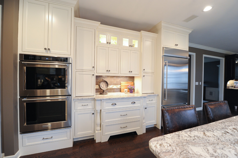 Exempel på ett stort klassiskt kök, med en rustik diskho, luckor med infälld panel, vita skåp, granitbänkskiva, brunt stänkskydd, stänkskydd i tunnelbanekakel, rostfria vitvaror, mörkt trägolv och en köksö