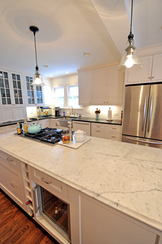Large trendy u-shaped eat-in kitchen photo in Cleveland with an undermount sink, shaker cabinets, white cabinets, marble countertops, white backsplash, subway tile backsplash and stainless steel appliances