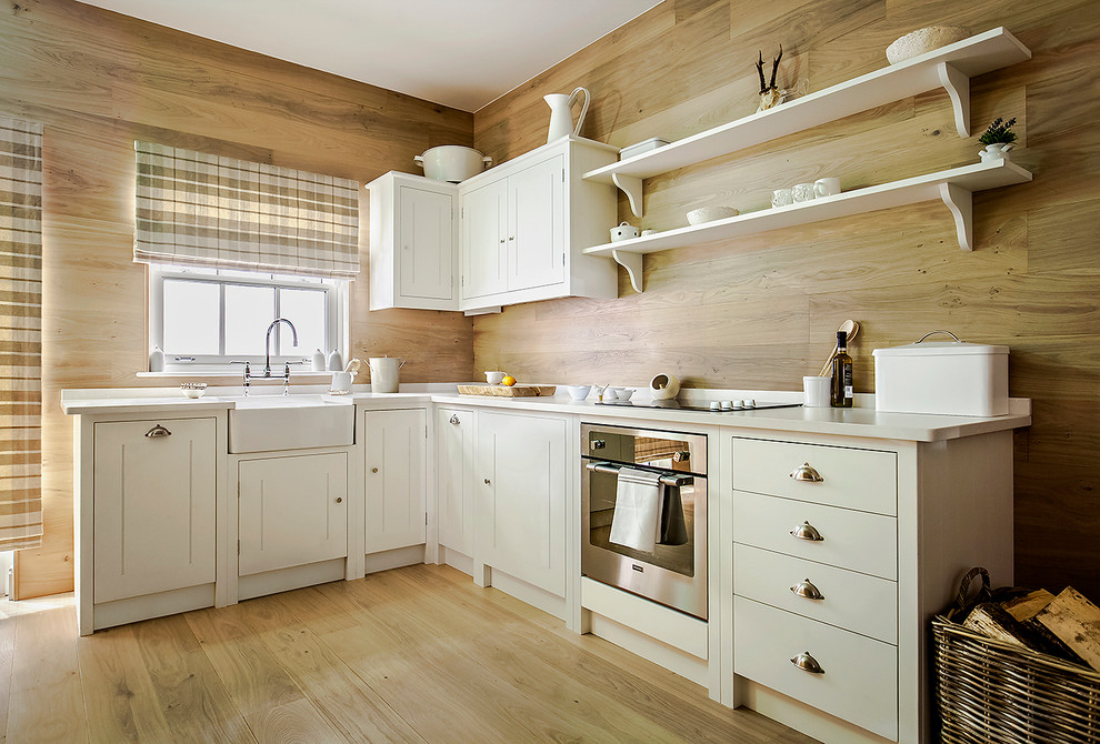 Example of a small country l-shaped light wood floor kitchen design in London with a farmhouse sink, beaded inset cabinets, white cabinets and stainless steel appliances