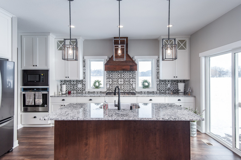 Foto på ett lantligt flerfärgad kök, med en undermonterad diskho, skåp i shakerstil, vita skåp, flerfärgad stänkskydd, rostfria vitvaror, mellanmörkt trägolv och en köksö