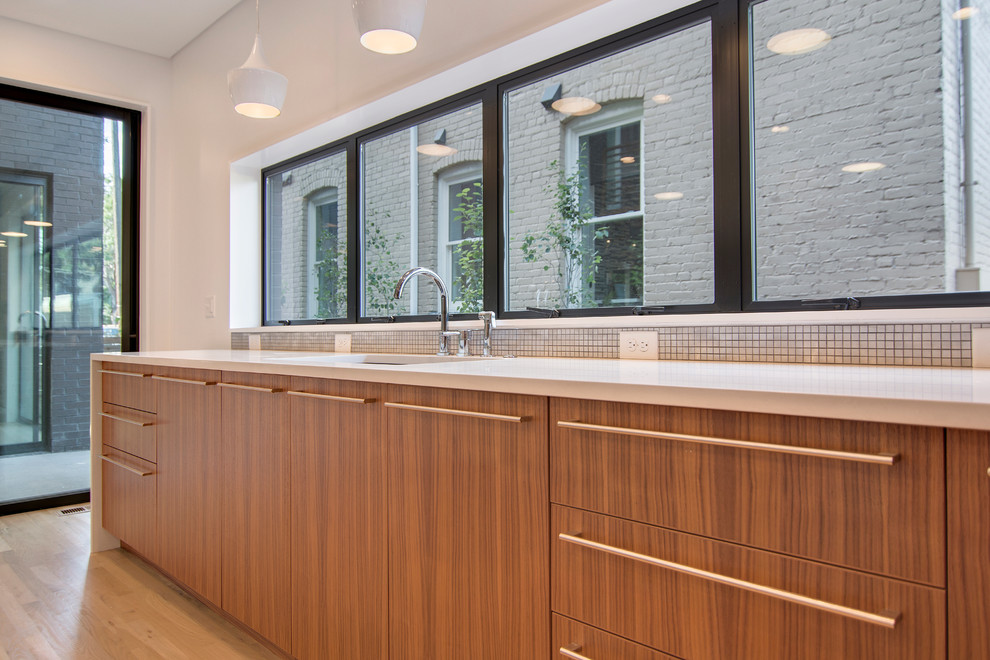 This is an example of a large contemporary l-shaped kitchen/diner in Denver with a submerged sink, flat-panel cabinets, dark wood cabinets, engineered stone countertops, metallic splashback, metal splashback, stainless steel appliances, light hardwood flooring and an island.