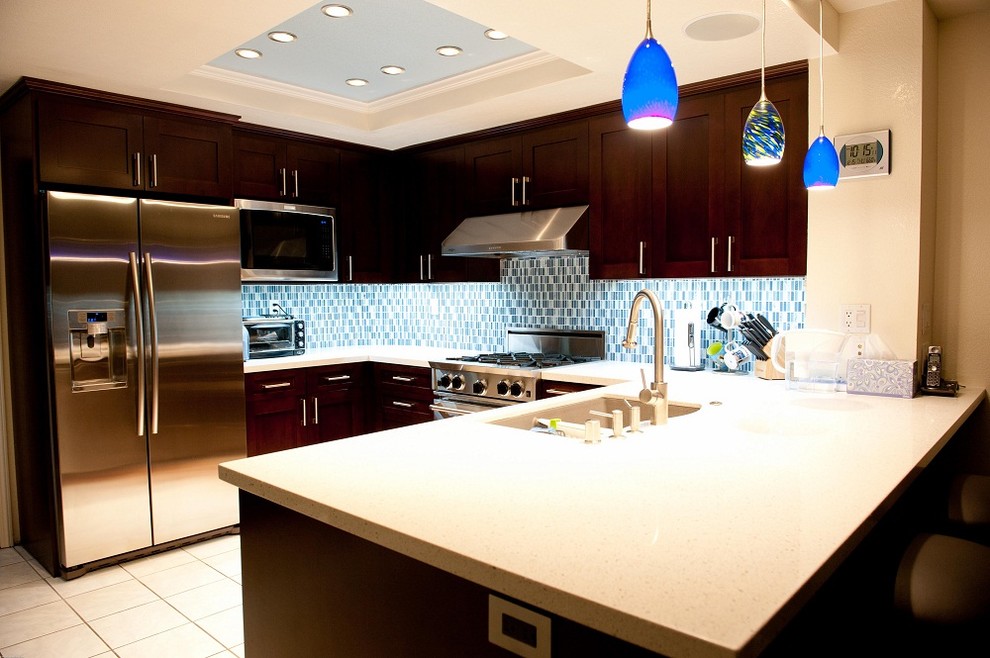 Inspiration for a contemporary u-shaped kitchen remodel in New York with a double-bowl sink, shaker cabinets, dark wood cabinets, blue backsplash, stainless steel appliances and no island