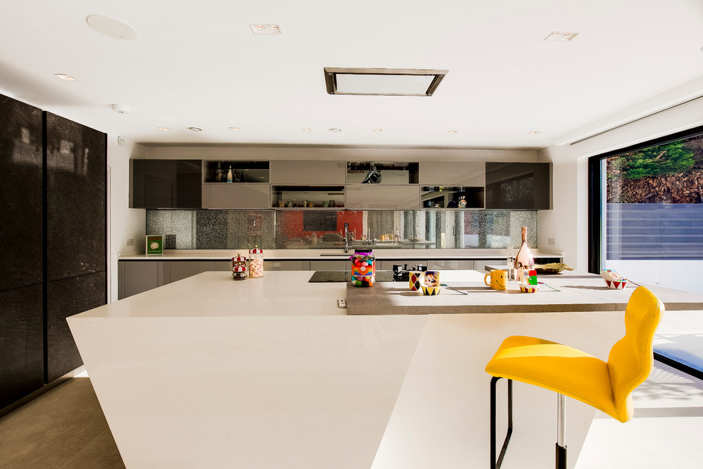Идея дизайна: огромная угловая кухня-гостиная в современном стиле с фартуком из стекла, черной техникой, мраморным полом и островом