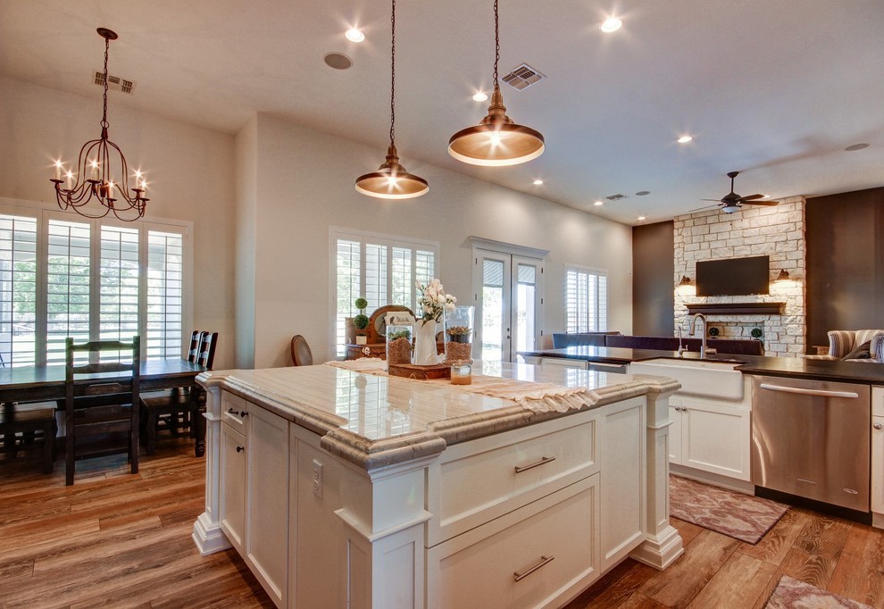Example of a large transitional u-shaped medium tone wood floor and brown floor eat-in kitchen design in Phoenix with a farmhouse sink, shaker cabinets, white cabinets, marble countertops, white backsplash, subway tile backsplash, stainless steel appliances, an island and multicolored countertops