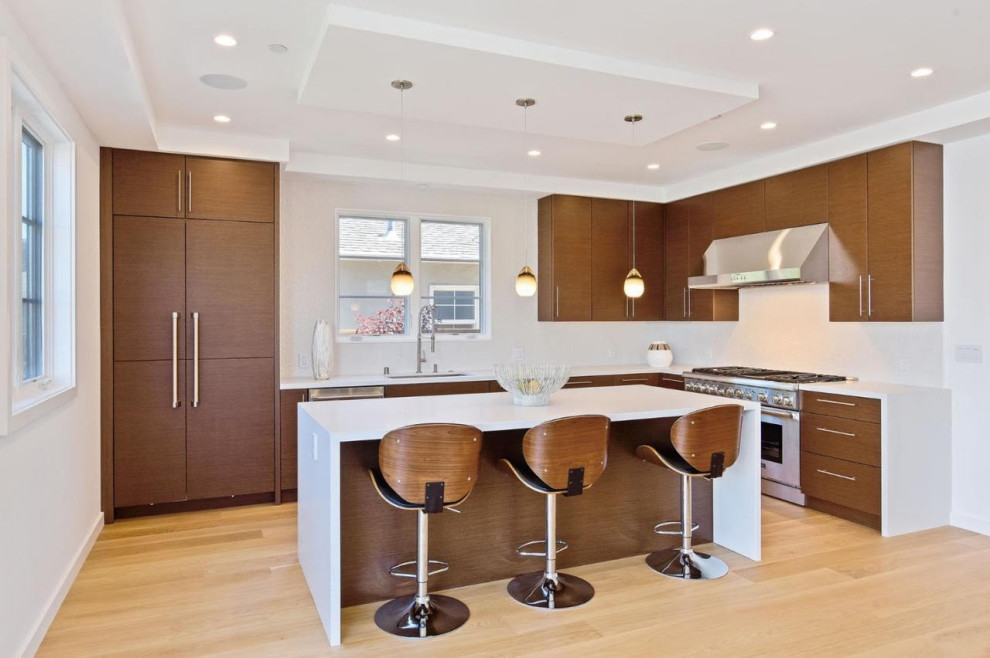 Bild på ett mellanstort funkis vit vitt kök, med en undermonterad diskho, släta luckor, bruna skåp, bänkskiva i kvarts, vitt stänkskydd, stänkskydd i porslinskakel, rostfria vitvaror, mellanmörkt trägolv, en köksö och beiget golv