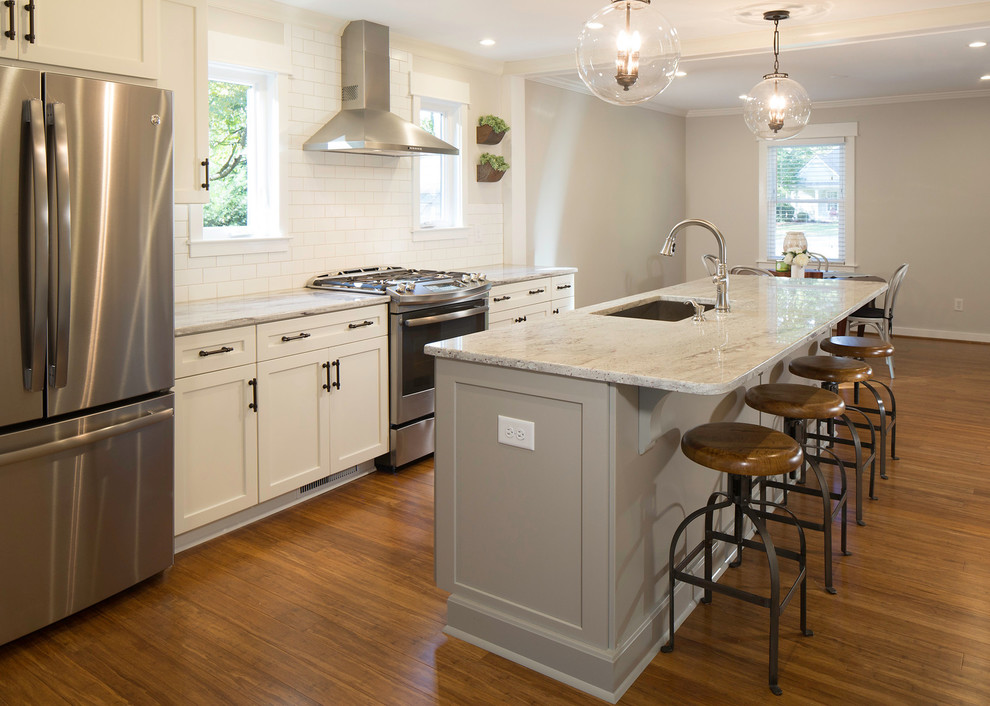 Exempel på ett mellanstort retro kök och matrum, med en undermonterad diskho, skåp i shakerstil, granitbänkskiva, vitt stänkskydd, stänkskydd i tunnelbanekakel, rostfria vitvaror, mellanmörkt trägolv, en köksö och brunt golv
