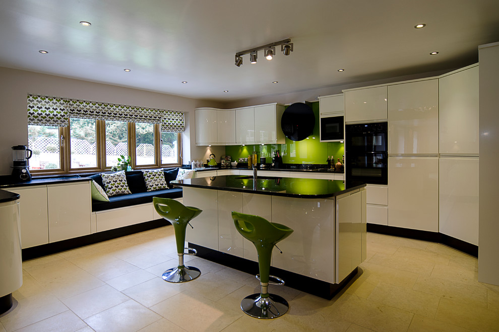 Medium sized contemporary u-shaped open plan kitchen in Other with an integrated sink, flat-panel cabinets, white cabinets, granite worktops, green splashback, glass sheet splashback, stainless steel appliances, limestone flooring and an island.