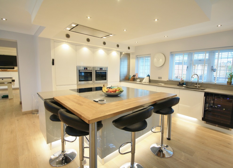 Große Moderne Wohnküche mit hellem Holzboden und Kücheninsel in Essex