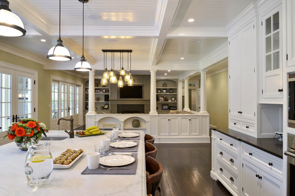 Idéer för ett stort klassiskt kök, med en dubbel diskho, luckor med infälld panel, vita skåp, marmorbänkskiva, vitt stänkskydd, stänkskydd i glaskakel, rostfria vitvaror och mörkt trägolv