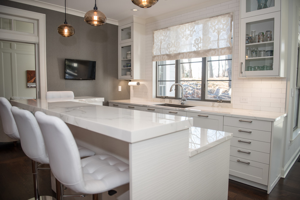 Eat-in kitchen - mid-sized contemporary u-shaped dark wood floor eat-in kitchen idea in New York with shaker cabinets, white cabinets, marble countertops, white backsplash, subway tile backsplash, stainless steel appliances and an island