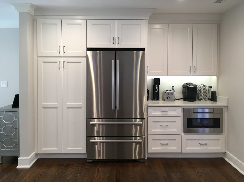 Photo of a traditional kitchen in New York with recessed-panel cabinets, white cabinets, stainless steel appliances and dark hardwood flooring.