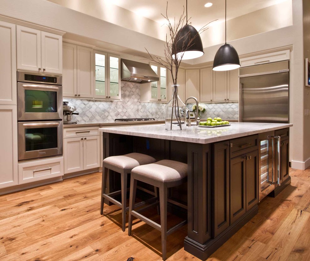 Example of a mid-sized transitional l-shaped medium tone wood floor eat-in kitchen design in Phoenix with a single-bowl sink, recessed-panel cabinets, beige cabinets, quartz countertops, gray backsplash, mosaic tile backsplash, stainless steel appliances and an island