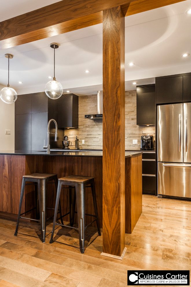 Bild på ett mellanstort funkis kök, med en integrerad diskho, släta luckor, svarta skåp, bänkskiva i kvartsit, grått stänkskydd, stänkskydd i stenkakel, rostfria vitvaror, mellanmörkt trägolv och en köksö