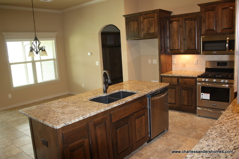 Inspiration for a small timeless l-shaped ceramic tile eat-in kitchen remodel in Other with a double-bowl sink, raised-panel cabinets, dark wood cabinets, granite countertops, brown backsplash, stone tile backsplash, stainless steel appliances and an island