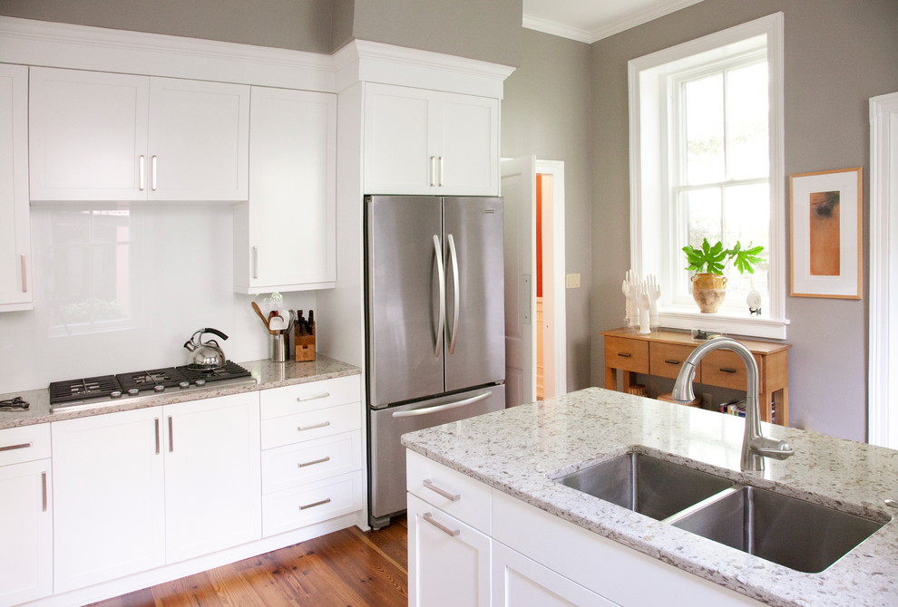 Inspiration for a timeless kitchen remodel in Charleston with a double-bowl sink, white cabinets, quartz countertops, white backsplash, glass sheet backsplash, stainless steel appliances and shaker cabinets