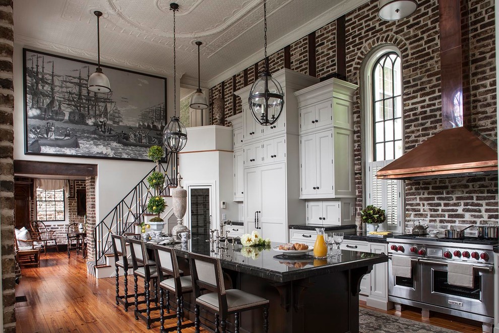 Large victorian galley kitchen in Charleston with recessed-panel cabinets, white cabinets, stainless steel appliances, medium hardwood flooring and an island.