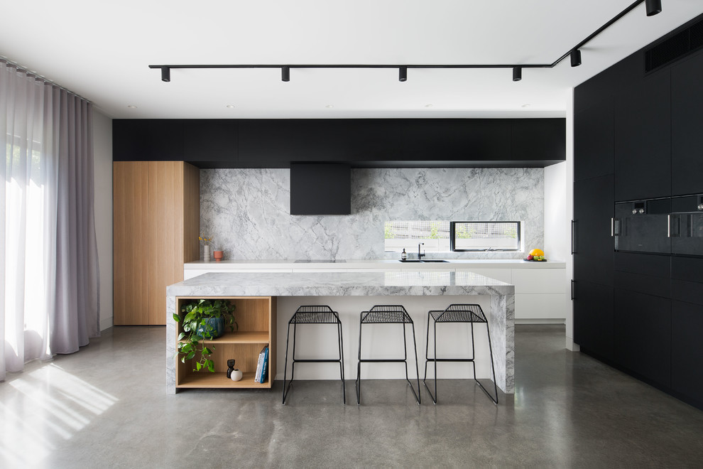Example of a danish l-shaped concrete floor and gray floor kitchen design in Melbourne with a double-bowl sink, flat-panel cabinets, white backsplash, black appliances, an island and white countertops