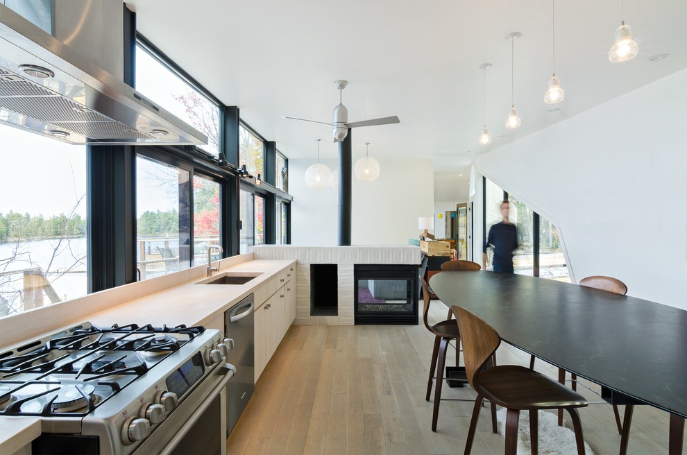Источник вдохновения для домашнего уюта: кухня-гостиная в скандинавском стиле с врезной мойкой, плоскими фасадами и светлыми деревянными фасадами