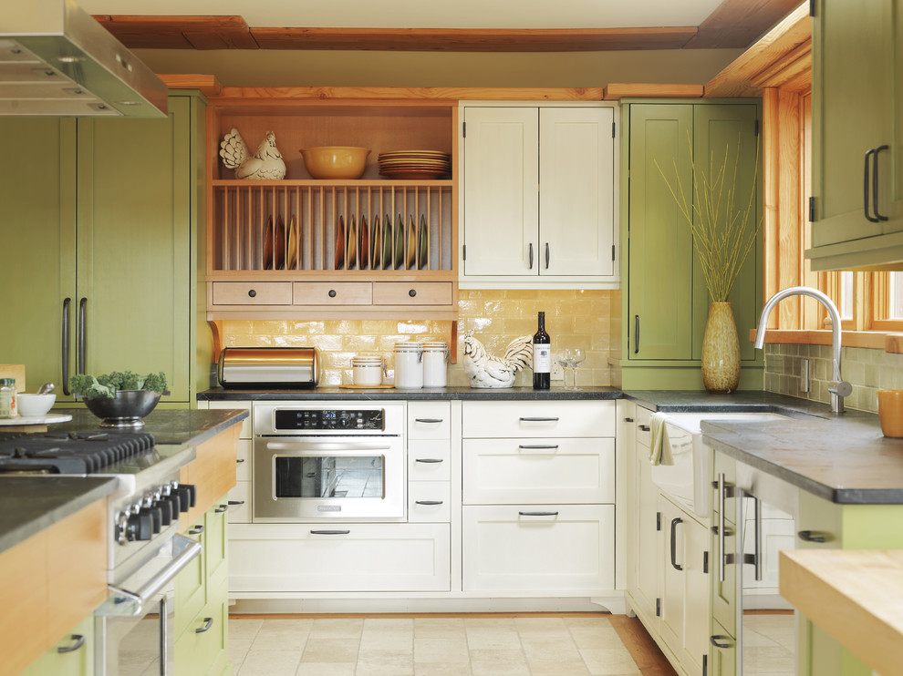 Foto på ett funkis kök, med rostfria vitvaror, bänkskiva i täljsten, gröna skåp, en rustik diskho, skåp i shakerstil och gult stänkskydd