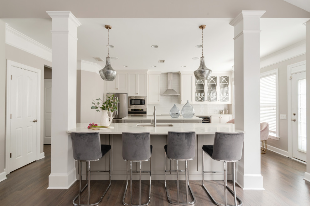 Example of a mid-sized transitional galley dark wood floor and brown floor eat-in kitchen design in Charlotte with a single-bowl sink, shaker cabinets, white cabinets, quartz countertops, gray backsplash, subway tile backsplash, stainless steel appliances, two islands and white countertops