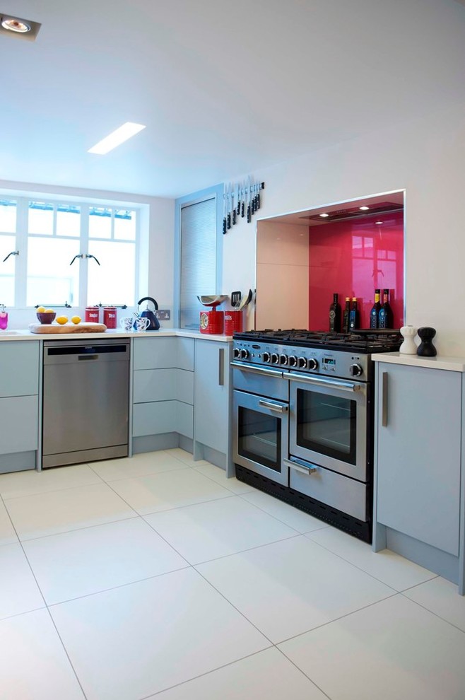 Modern inredning av ett kök och matrum, med en undermonterad diskho, släta luckor, blå skåp, bänkskiva i kvarts, rosa stänkskydd, glaspanel som stänkskydd, rostfria vitvaror och klinkergolv i porslin