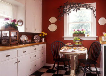 Bild på ett avskilt, litet vintage l-kök, med släta luckor, vita skåp, träbänkskiva och linoleumgolv