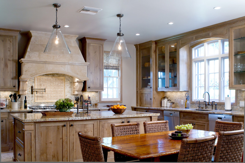 На фото: кухня в классическом стиле с стеклянными фасадами, гранитной столешницей, обеденным столом, светлыми деревянными фасадами, бежевым фартуком, фартуком из известняка и барной стойкой с
