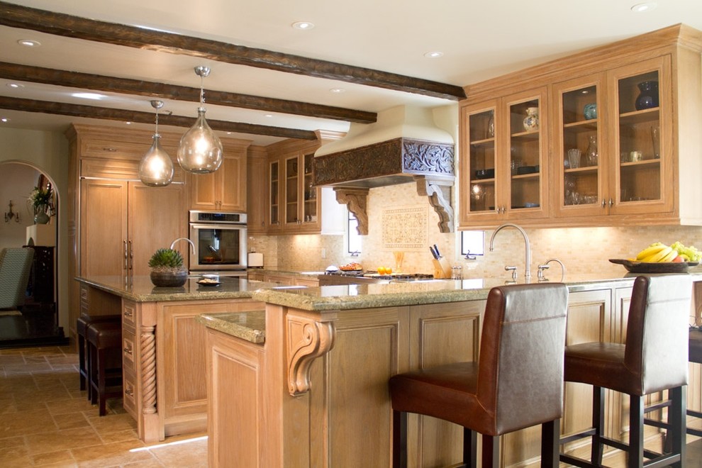 Photo of a mediterranean u-shaped kitchen in Los Angeles with glass-front cabinets, light wood cabinets, granite worktops, beige splashback and integrated appliances.