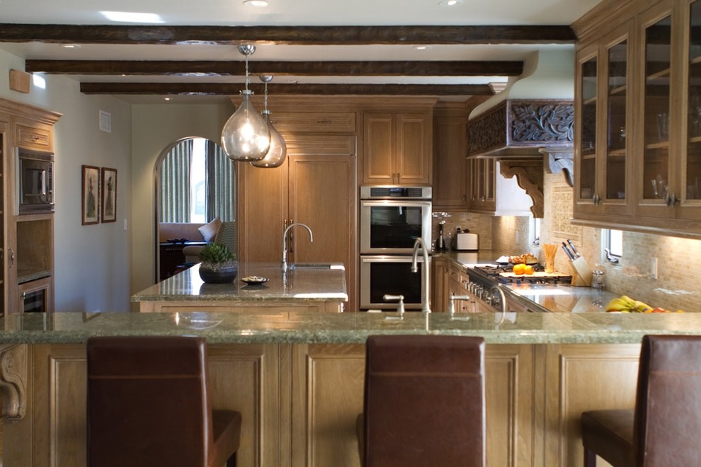 Cette image montre une cuisine encastrable chalet en U et bois brun avec une crédence en mosaïque, un placard à porte vitrée, un plan de travail en granite et une crédence beige.
