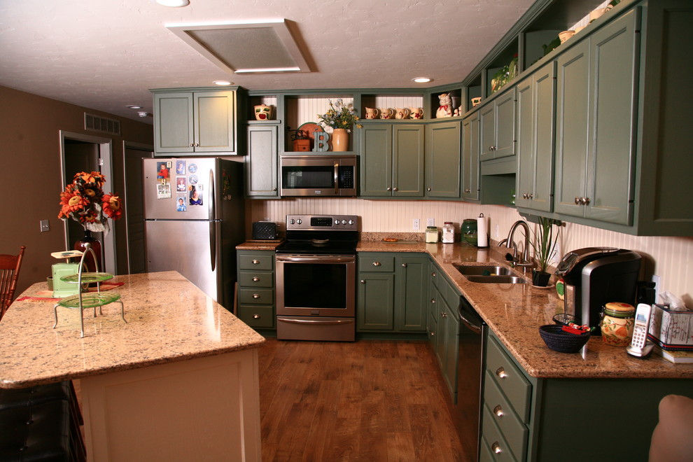Foto på ett mellanstort funkis kök, med en dubbel diskho, skåp i shakerstil, gröna skåp, granitbänkskiva, vitt stänkskydd, rostfria vitvaror, mörkt trägolv och en köksö