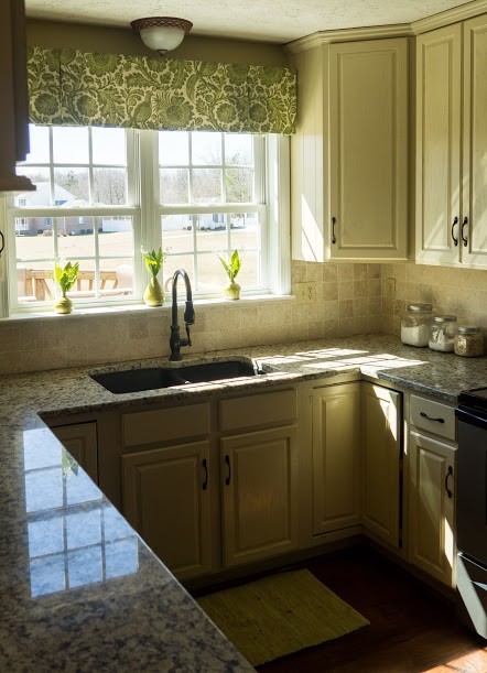 Bild på ett avskilt, mellanstort lantligt u-kök, med en dubbel diskho, luckor med upphöjd panel, vita skåp, granitbänkskiva, beige stänkskydd, stänkskydd i stenkakel, svarta vitvaror, mellanmörkt trägolv och en halv köksö