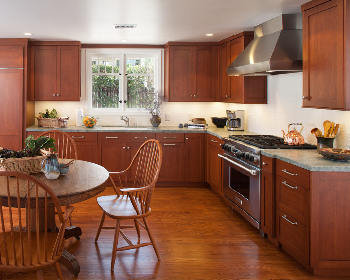 Inspiration for a large timeless l-shaped medium tone wood floor eat-in kitchen remodel in San Diego with an undermount sink, shaker cabinets, medium tone wood cabinets, granite countertops, white backsplash, ceramic backsplash and stainless steel appliances