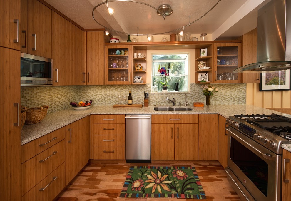 Bild på ett litet vintage kök, med en undermonterad diskho, släta luckor, skåp i mellenmörkt trä, bänkskiva i återvunnet glas, grönt stänkskydd, rostfria vitvaror, mellanmörkt trägolv och en halv köksö